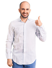 Wall Mural - Young handsome man wearing elegant shirt smiling happy and positive, thumb up doing excellent and approval sign