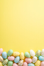 Easter Concept. Top View Vertical Photo Of Colorful Easter Eggs On Isolated Yellow Background With Empty Space