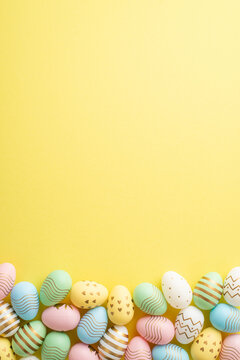 easter concept. top view vertical photo of colorful easter eggs on isolated yellow background with e
