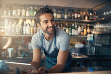 Aufkleber - Business is right where he wants it. Shot of a young man using a digital tablet while working behind a bar counter.