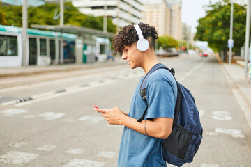 latin teenage boy using mobile phone while walking down the city street