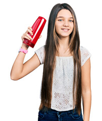 Sticker - Young brunette girl with long hair holding shampoo bottle looking positive and happy standing and smiling with a confident smile showing teeth