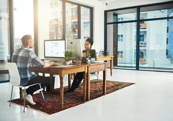 Poster - Working opposite a colleague. Full length shot of two businesspeople working on opposite ends of a desk in the office.