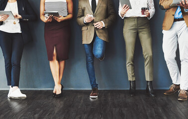 Poster - Getting their feet into the door of business. Cropped studio shot of a group of businesspeople using wireless technology while waiting in line against a gray background.