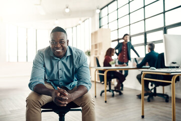 Wall Mural - Passion for my occupation Check. Portrait of a young businessman sitting in a modern office with his colleagues working in the background.