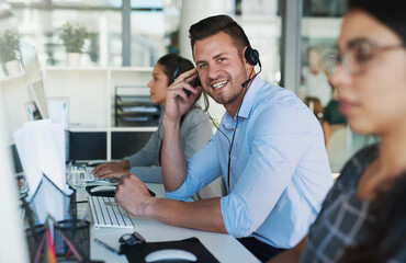 Wall Mural - Customer care you can count on. Portrait of a happy and confident young man working in a call center.