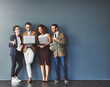 © Donson/peopleimages.com - The connected team is an efficient team. Studio shot of a group of businesspeople using wireless technology together while standing in line against a gray background.