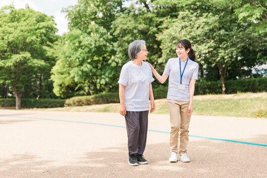 公園で運動・ウォーキング・歩く高齢者と介護士・看護師・理学療法士・運動指導員の女性