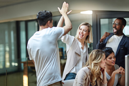 weve done it again. shot of a group of colleagues giving each other a high five while using a comput