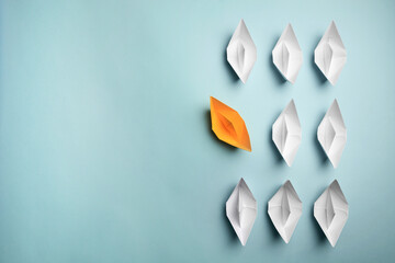 Wall Mural - Yellow paper boat floating away from others on light background, flat lay with space for text. Uniqueness concept