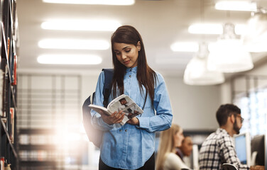 Fototapete - All this info is so intriguing. Shot of a university student reading a book in the library at campus.