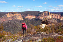 Female Taking In Magnificent Vistas Of Sheer Sandstone Cliffs Across The Valley