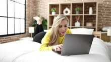 Young Blonde Woman Using Laptop Lying On Bed At Bedroom