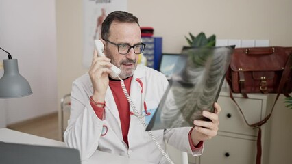 Sticker - Middle age man doctor talking on telephone looking xray at clinic