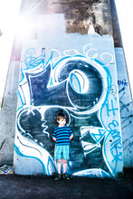 A Boy Stands Next To Grafitti Saying LOVE Under A Bridge In Seattle.