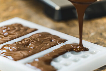 chocolate making workshop. milk chocolate being poured into moulds to create bars in different shape