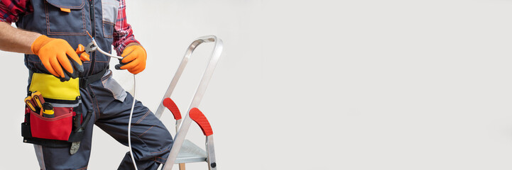 Wall Mural - Electrician with tools and cable standing over white background. Banner, long format.