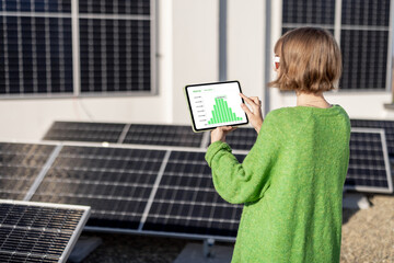 young woman monitors energy production from the solar power plant with a digital tablet. view on tab