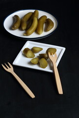 Cucumber pickles in a plate on a black background