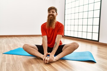 Sticker - Young redhead man smiling confident stretching at sport center