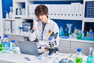 Sticker - Young hispanic man scientist talking on the smartphone using laptop at laboratory