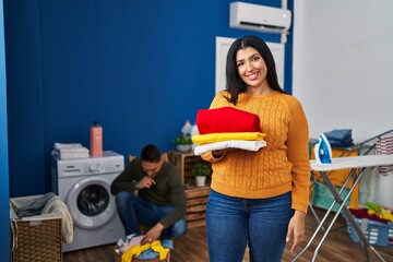 Sticker - Young couple doing laundry at home looking positive and happy standing and smiling with a confident smile showing teeth