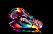 A Light Bulb, Isolated On A Black Background, With Abstract Reflections On It.