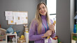 Young blonde woman preschool teacher smiling confident holding checklist at kindergarten