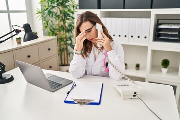 Canvas Print - Young woman wearing doctor uniform stressed talking on the telephone at clinic