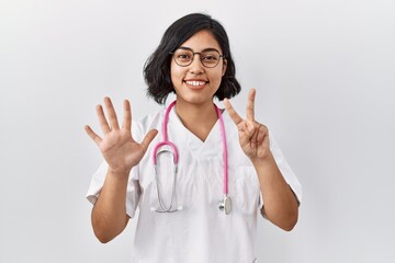 Sticker - Young hispanic doctor woman wearing stethoscope over isolated background showing and pointing up with fingers number seven while smiling confident and happy.