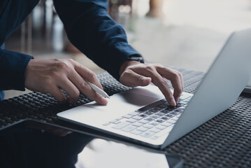 Canvas Print - Business man working on laptop computer, hand typing keyboard. Casual business man, freelancer online working at coffee shop, surfing the internet