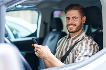 Young caucasian man using smartphone sitting on car at street