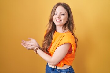 Sticker - Caucasian woman standing over yellow background pointing aside with hands open palms showing copy space, presenting advertisement smiling excited happy