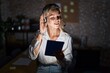 © Krakenimages.com - Young blonde woman working at the office at night smiling with hand over ear listening an hearing to rumor or gossip. deafness concept.