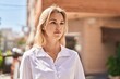 © Krakenimages.com - Young blonde woman with relaxed expression standing at street
