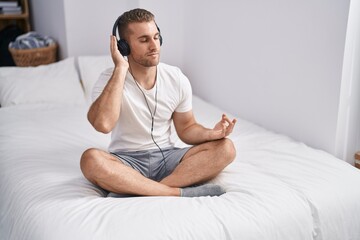 Poster - Young caucasian man doing yoga exercise sitting on bed at bedroom