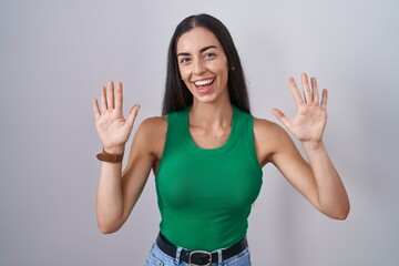 Sticker - Young woman standing over isolated background showing and pointing up with fingers number ten while smiling confident and happy.