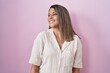 © Krakenimages.com - Blonde woman standing over pink background looking away to side with smile on face, natural expression. laughing confident.