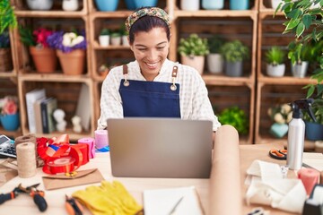 Canvas Print - Young beautiful hispanic woman florist smiling confident using laptop at florist