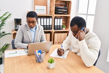 Canvas Print - Man and woman business workers using laptop and talking on the smartphone at office