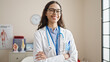 © Krakenimages.com - Young beautiful hispanic woman doctor smiling confident standing with crossed arms at clinic