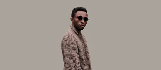 portrait of stylish young african man model wearing knitted cardigan isolated on gray background