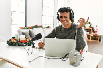 Sticker - Young hispanic man radio worker working sitting by christmas tree at home