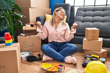 Wall Mural - Young hispanic woman moving to a new home sitting on the floor celebrating surprised and amazed for success with arms raised and eyes closed. winner concept.