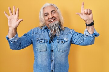 Poster - Middle age man with grey hair standing over yellow background showing and pointing up with fingers number seven while smiling confident and happy.