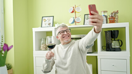 Poster - Middle age grey-haired man drinking glass of wine taking selfie by smartphone at home