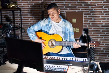 Canvas Print - Hispanic young man playing classic guitar at music studio depressed and worry for distress, crying angry and afraid. sad expression.