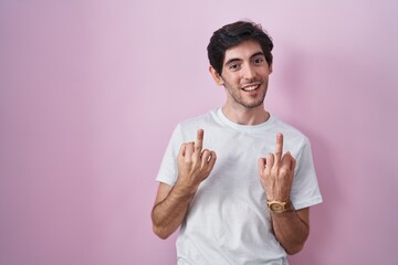 Poster - Young hispanic man standing over pink background showing middle finger doing fuck you bad expression, provocation and rude attitude. screaming excited