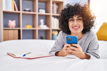 Sticker - Young middle east woman using smartphone lying on bed at bedroom