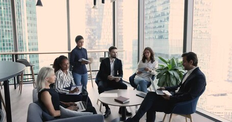 Sticker - Group of multi ethnic employees listen company chief during morning briefing in skyscraper building. Team leader share opinion, corporate goal, talk about collaborative project to diverse office staff